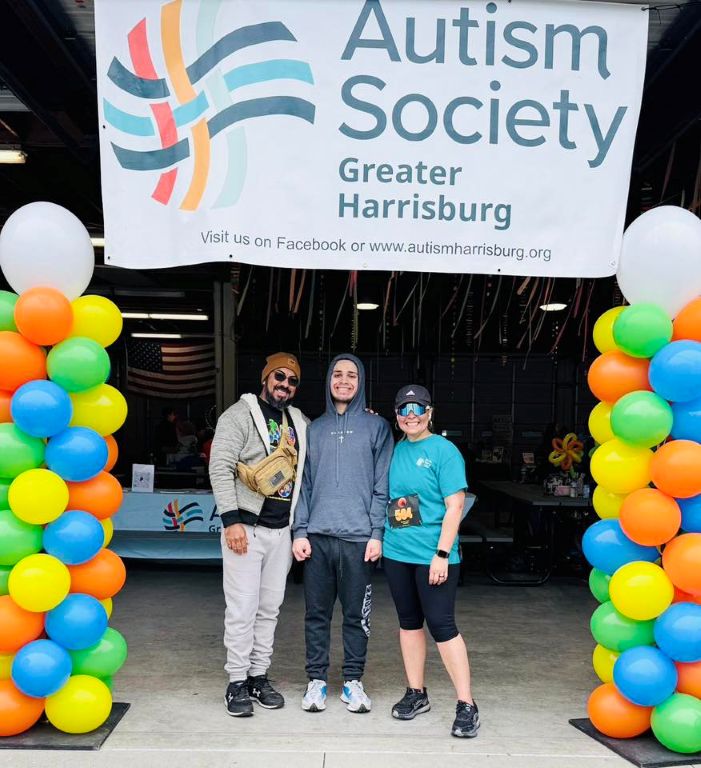Picture of three happy individuals standing underneath the Autism Society Greater Harrisburg Area at Logan's Run on City Island, Harrisburg, PA, April 25, 2026.